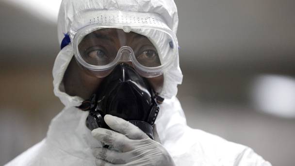 A Nigerian health official wearing a protective suit waits to screen passengers at the arrivals hall in Lagos.
