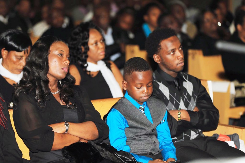 The family of the late Henry Gichaba, wife Jackline and sons Tylor and Trevor, look on during the sendoff memorial service at the Kenyan Community SDA Church in Brooklyn Center, Minnesota on Sunday, November 15 2015. Gichaba was found dead in his apartment the morning of Tuesday, November 3, 2015. Photo: Courtesy of KDR TV