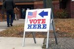 Vote Here Sign in Minneapolis on Election Day by Jasmine Webber of Mshale Newspaper Vote Here sign outside a Minneapolis polling location as people walk toward the building during a previous election